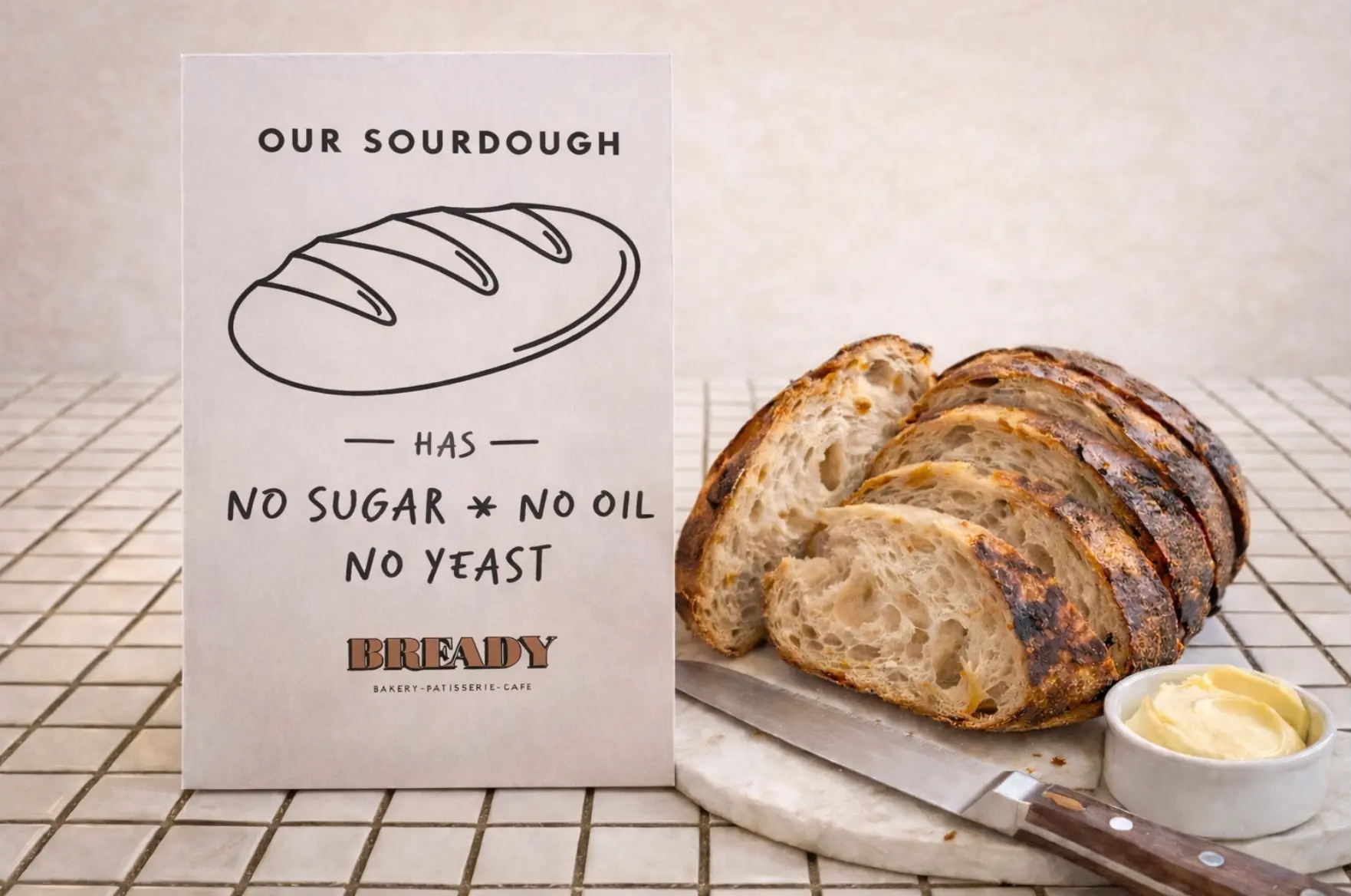 A sliced Bready sourdough loaf beside the OUR SOURDOUGH sign